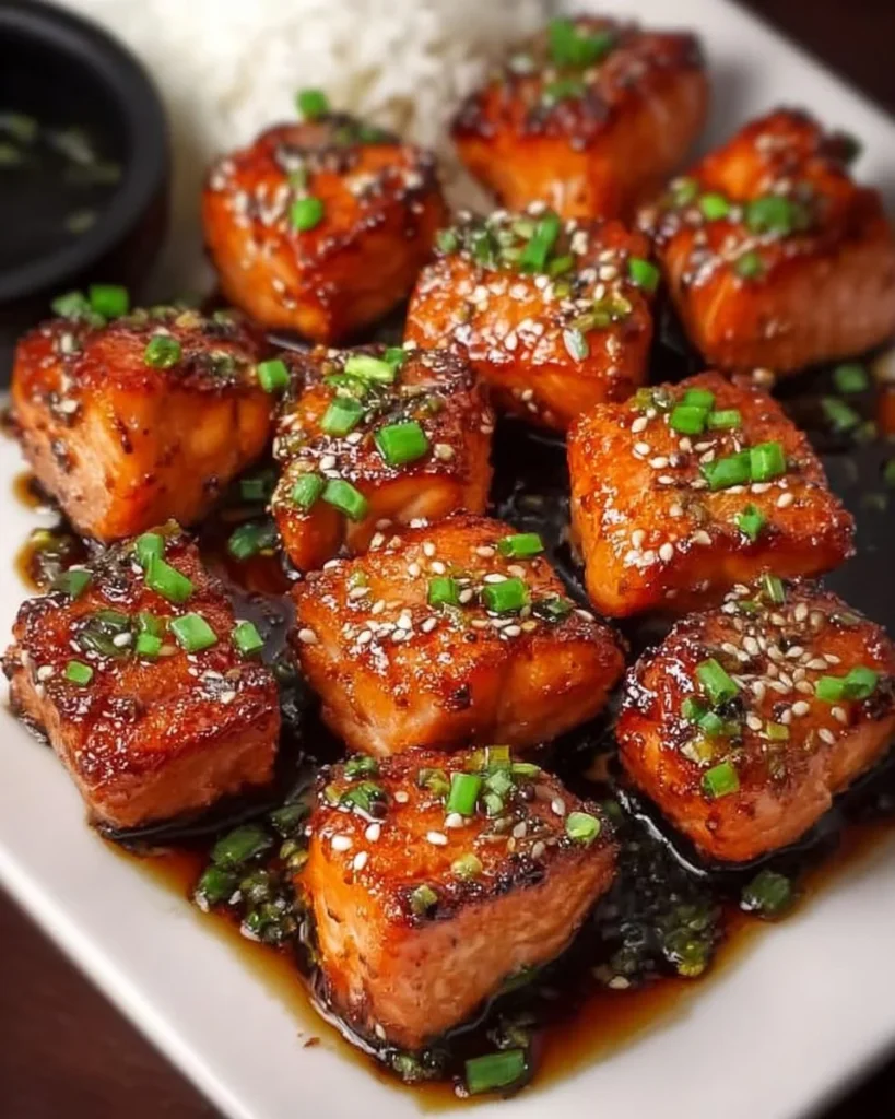 Delicious honey garlic salmon bites garnished with herbs on a serving platter.