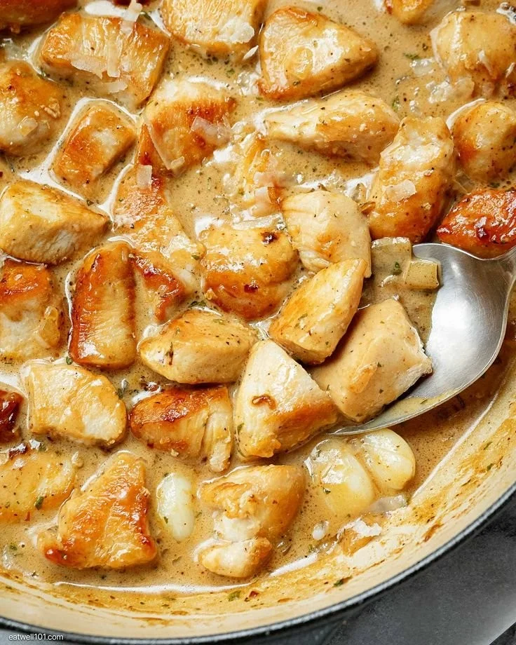 Creamy chicken bites in a rich sauce, served on a plate.
