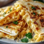 Creamy mac and cheese quesadillas served on a plate, garnished with herbs