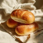 Freshly baked homemade sourdough hot dog buns on a wooden table