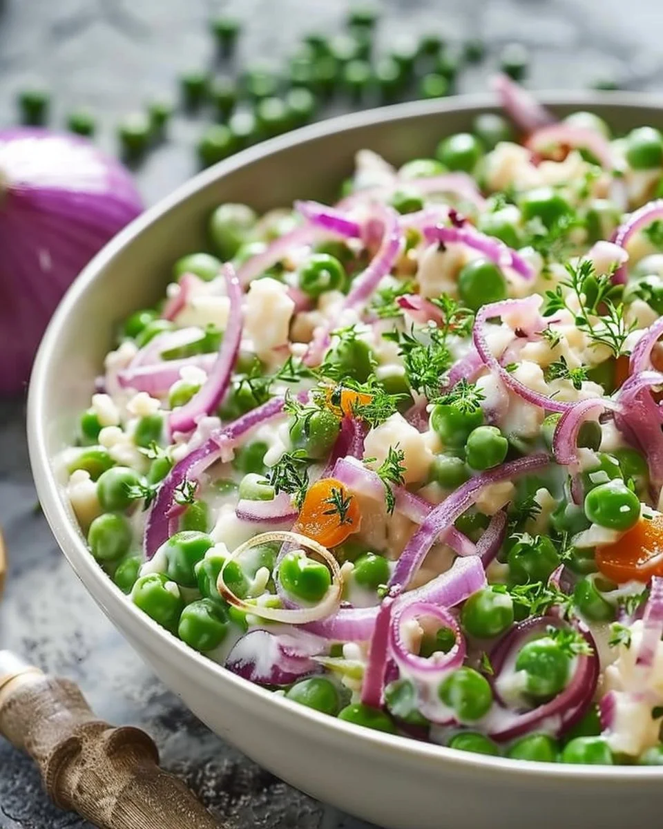 Pea salad with red onions, cheese, and a vibrant dressing in a bowl