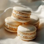 Delicious vanilla macarons on a white plate, perfect for dessert lovers.